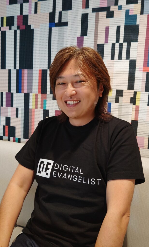 金谷武明が、株式会社Digital EvangelistのロゴがデザインされたTシャツを着て嬉しそう。